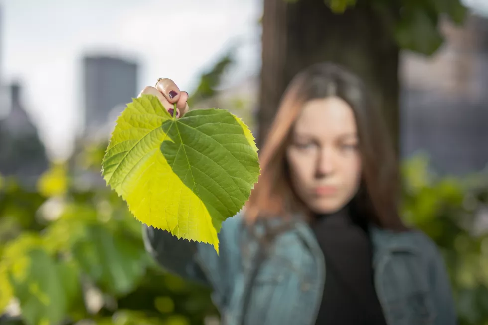 portrait-young-woman-holding-leaf-city