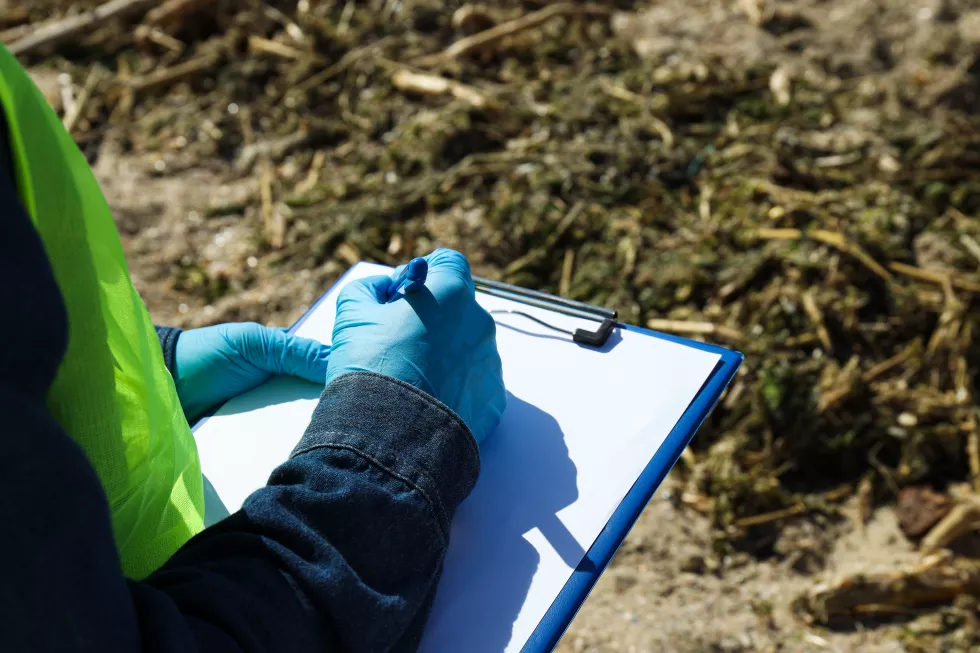 man-examines-pollution-reservoir-takes-notes