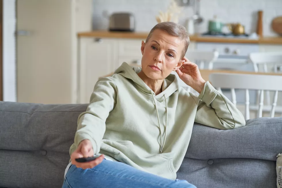 happy-middle-aged-woman-watching-tv-while-sitting-sofa-home