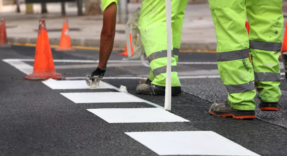 worker-reflective-pants-removes-thermoplastic-marking-tape-from-road-works-paint-traffic-lines