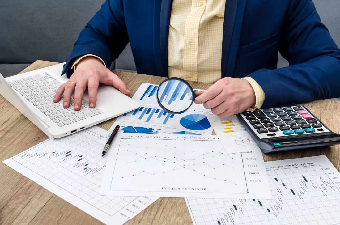 businessman-analyzing-business-graphs-with-magnifying-glass