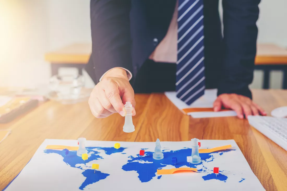 hand-businessman-playing-chess-with-world-map-as-board-business-strategy-concept(1)