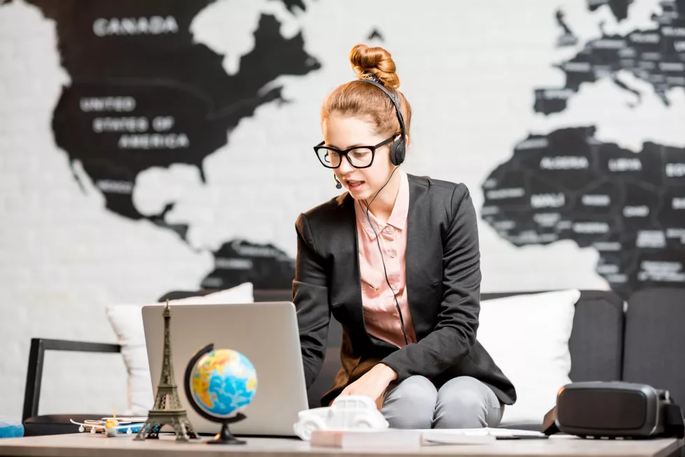 portrait-female-travel-agent-suit-headset-working-indoors-world-map-background
