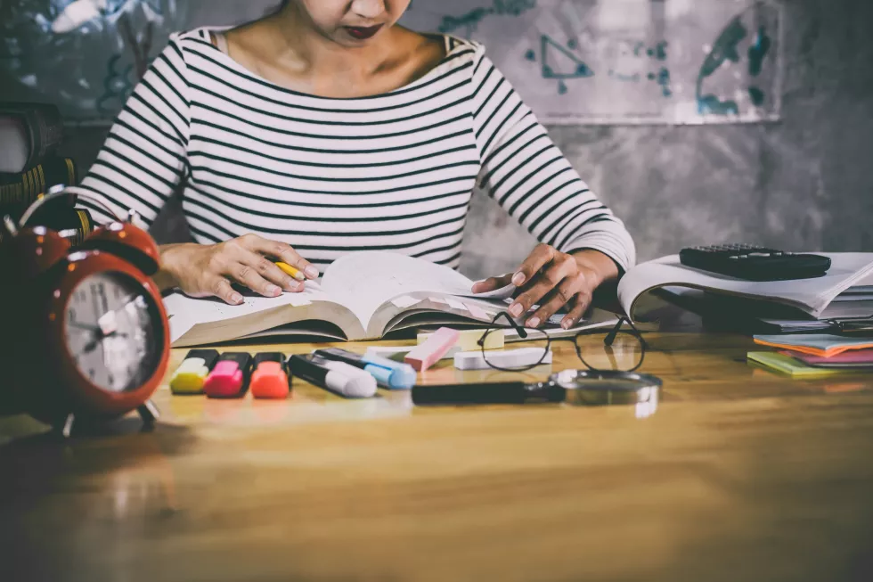 midsection-woman-reading-book-while-sitting-table