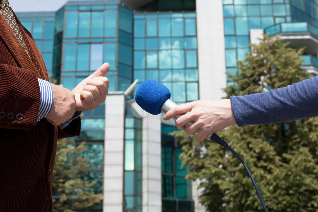 journalist-holding-microphone-while-taking-interview-businessman