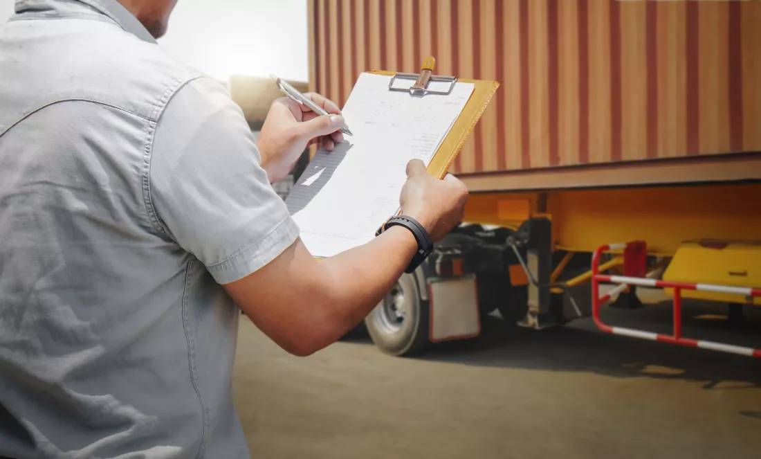 worker-holds-clipboard-controlling-loading-cargo-into-shipping-containers-logistics-trucks