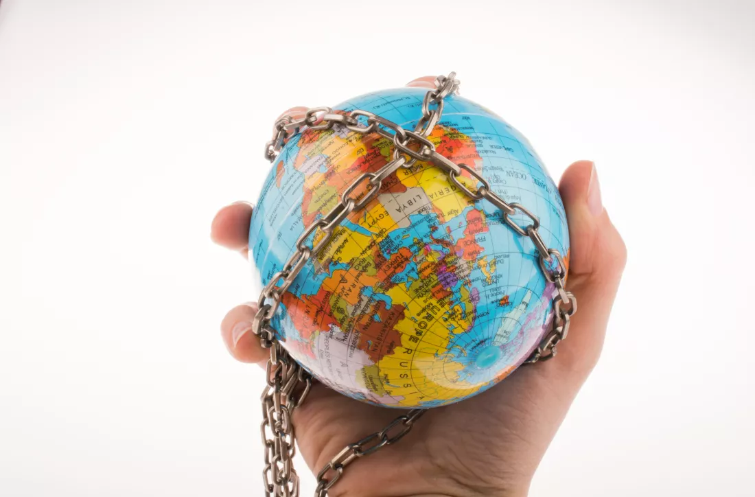 cropped-hand-holding-globe-with-chain-against-white-background