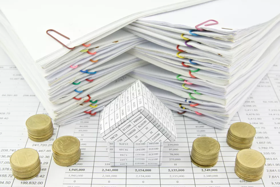 high-angle-view-papers-stacked-by-model-home-coins-table