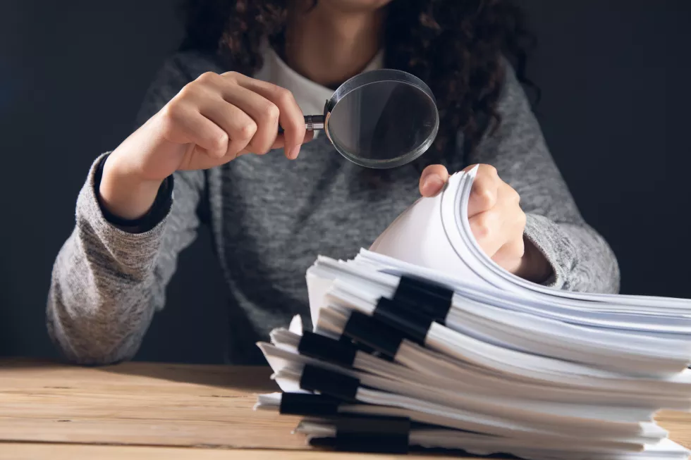 business-woman-holding-magnifying-glass-documents