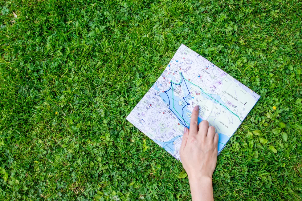 hand-holding-paper-sheet-with-travel-map-green-forest-nature-background