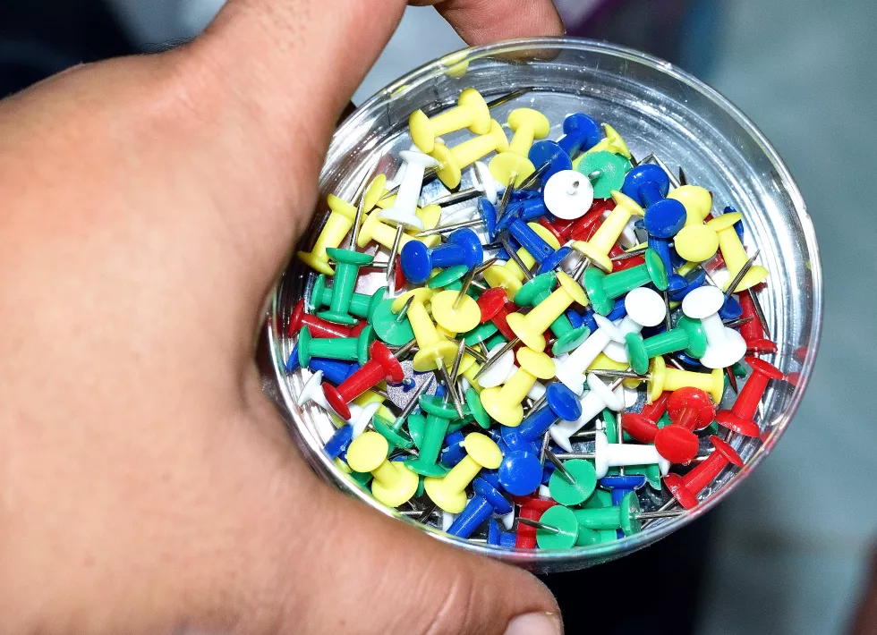 cropped-hand-colorful-straight-pins-container