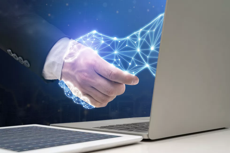 businessman-shaking-hands-with-digital-partner-extending-from-laptop-computer-futuristic-background