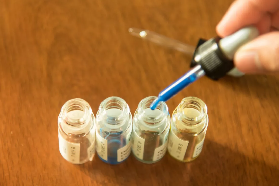 cropped-hand-holding-pipette-table