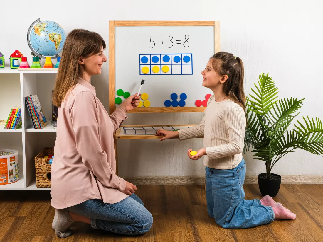 young-girl-her-teacher-are-sitting-near-magnetic-board-learning-math-with-counters-frames