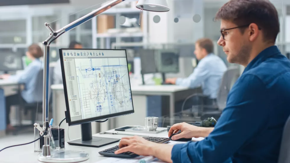 man-sits-desk-front-computer-screen-that-says-company-is