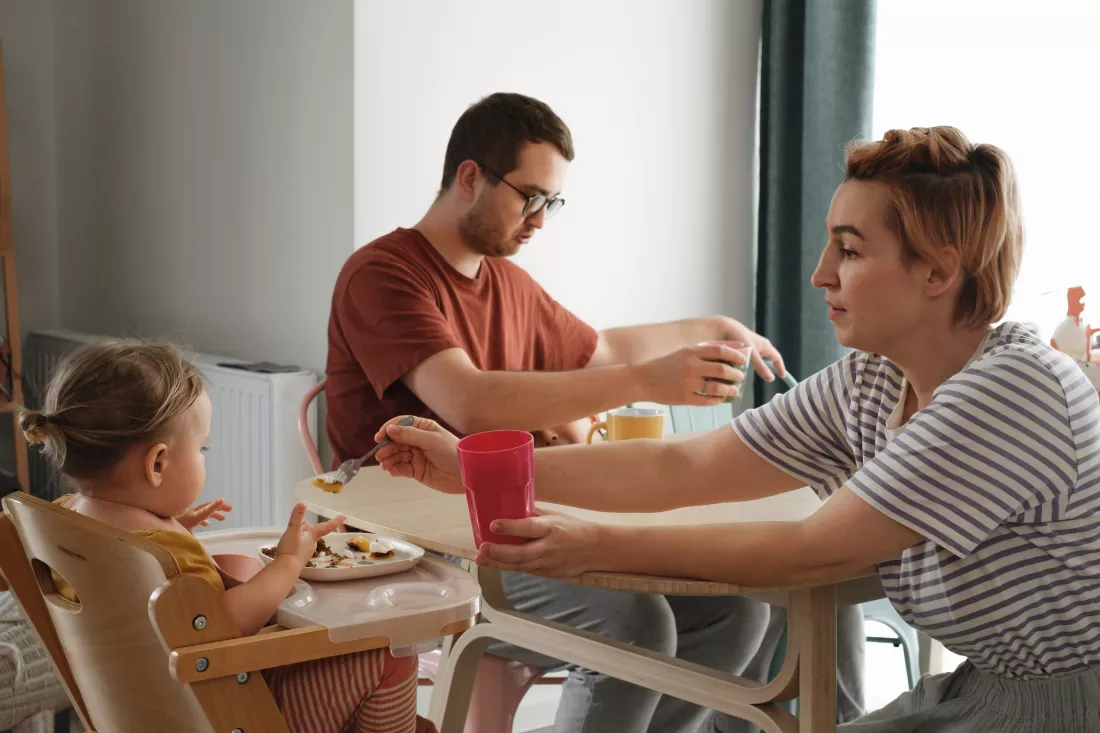 parents-with-children-having-meal-breakfast-by-table-mother-serving-food-family-home