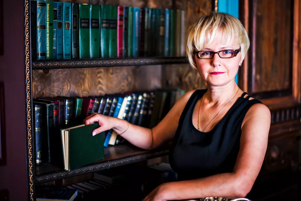 close-up-portrait-middle-aged-businesswoman-with-glasses-bookshelves-smiling
