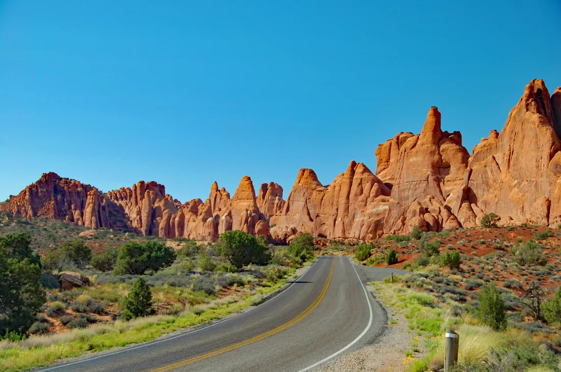 empty-road-leading-towards-mountain-against-blue-sky