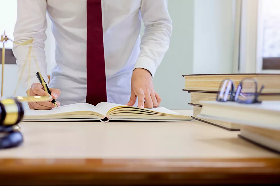 midsection-lawyer-reading-book-table-while-standing-office