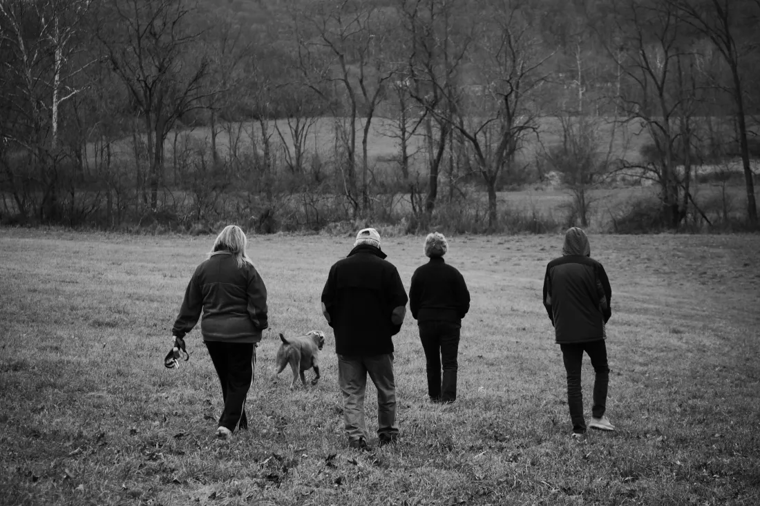 rear-view-men-women-with-dog-walking-field