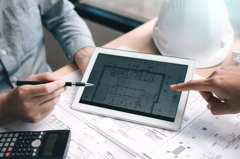 high-angle-view-architects-pointing-blueprint-digital-tablet