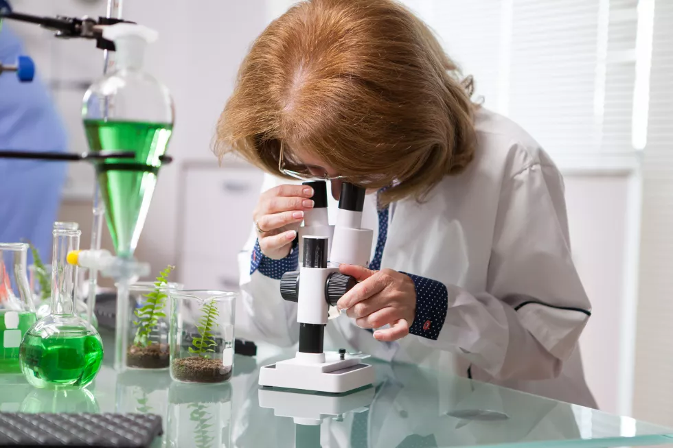 portrait-middle-age-female-biotechnology-scientist-working-microscope-scientific-test