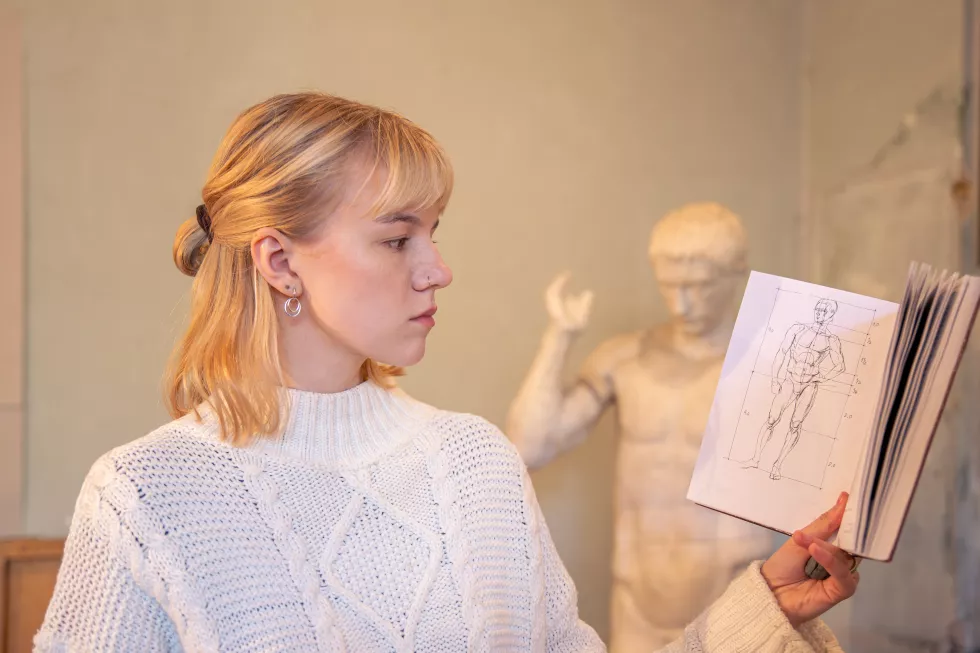 young-attractive-female-artist-reading-anatomy-book-learning-concept(1)