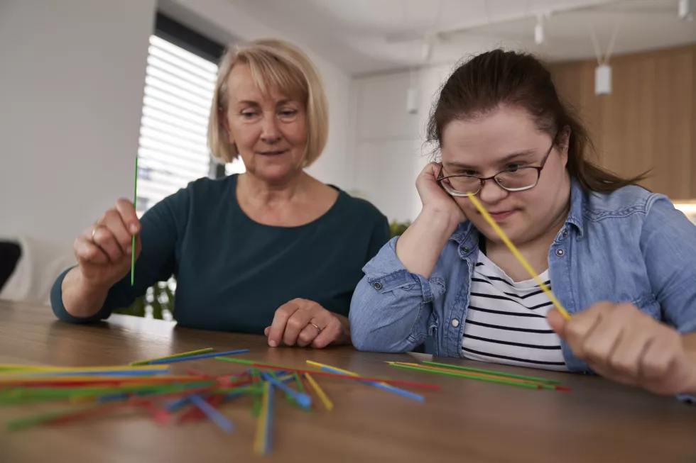 down-syndrome-woman-her-mother-playing-pick-up-sticks-home