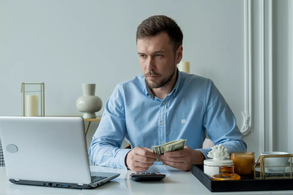 man-with-money-calculator-checks-bills-calculates-expenses-studies-credit-balance-sitting-table-home