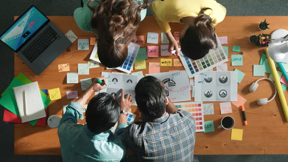 top-view-skilled-designer-holding-logo-while-discussing-with-team-symposium