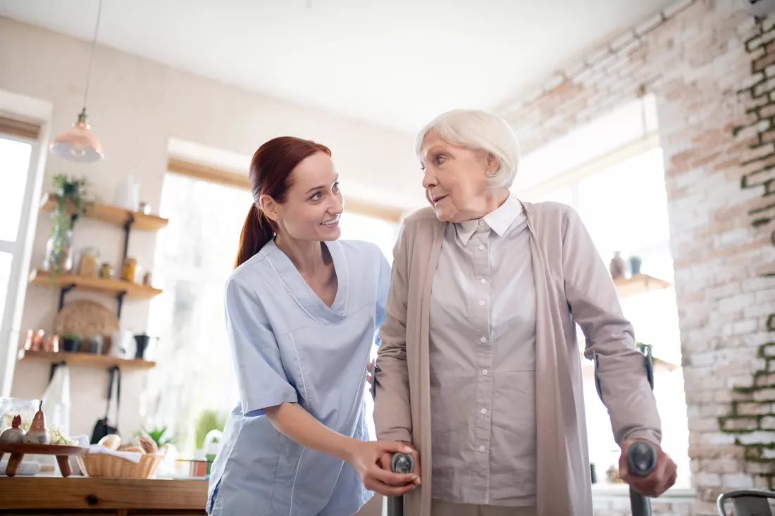 red-haired-female-caregiver-supporting-woman-with-crutches