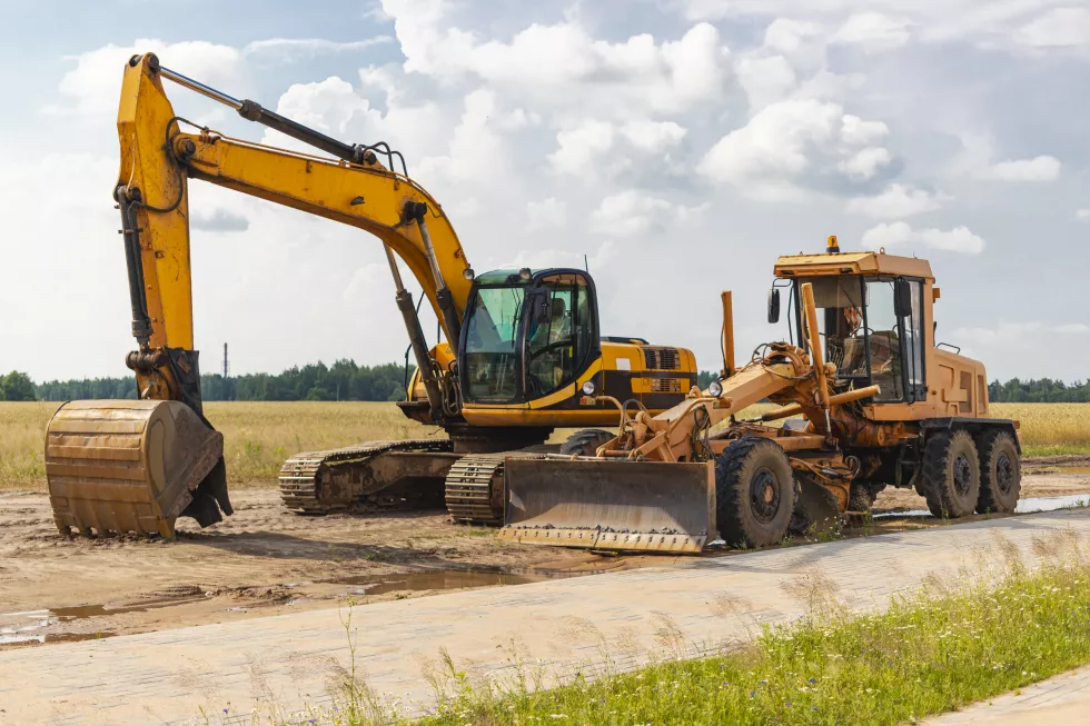 excavator-grader-stand-side-by-side-against-blue-sky-heavy-construction-earthmoving-equipment-construction-roads-underground-communications-construction-industry