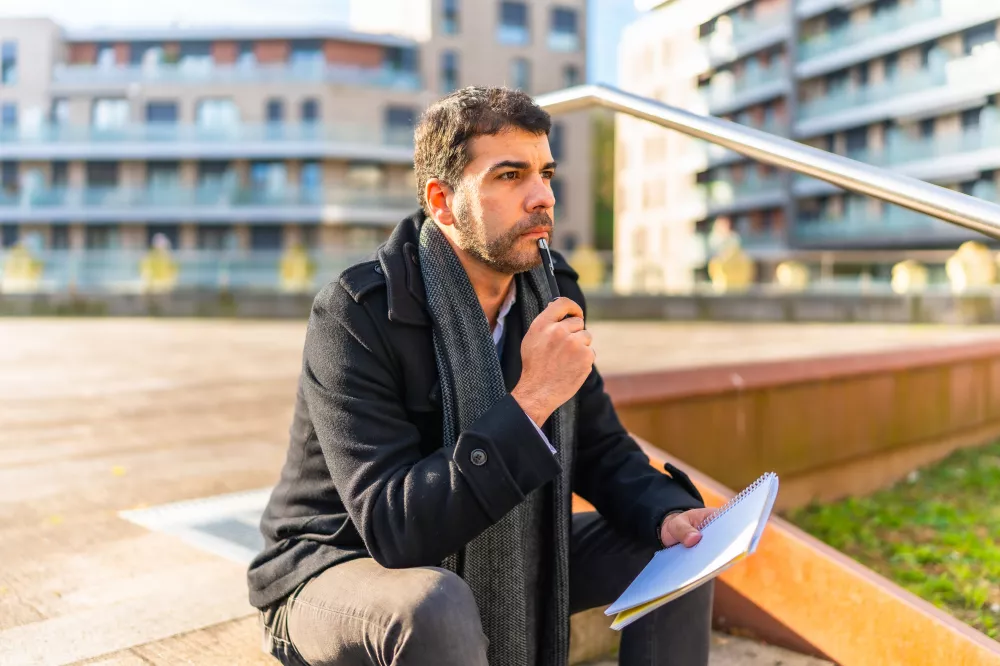 pensive-casual-businessman-writing-notes-sitting-outdoors-autumn