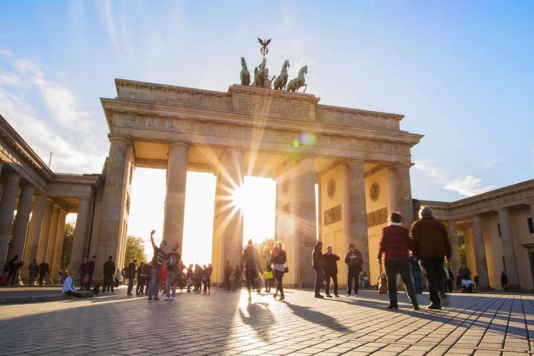 Ludzie spacerujący przed Bramą Brandenburską w Berlinie w słońcu