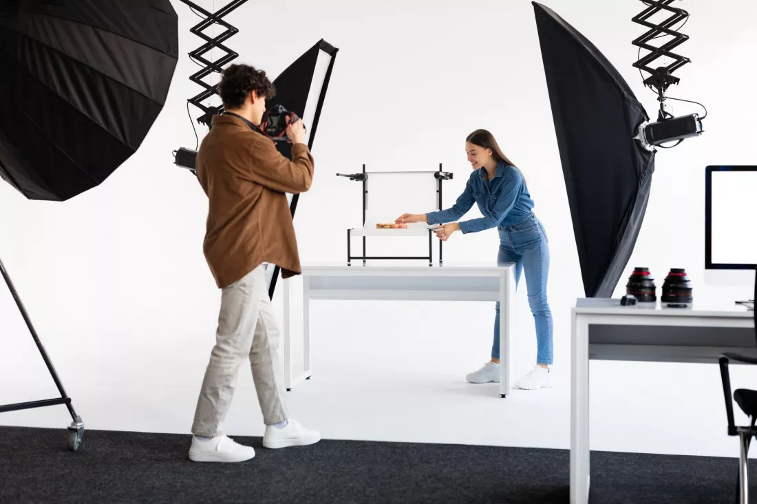 Fotograf i asystentka przygotowuja sesje produktowa w studiu