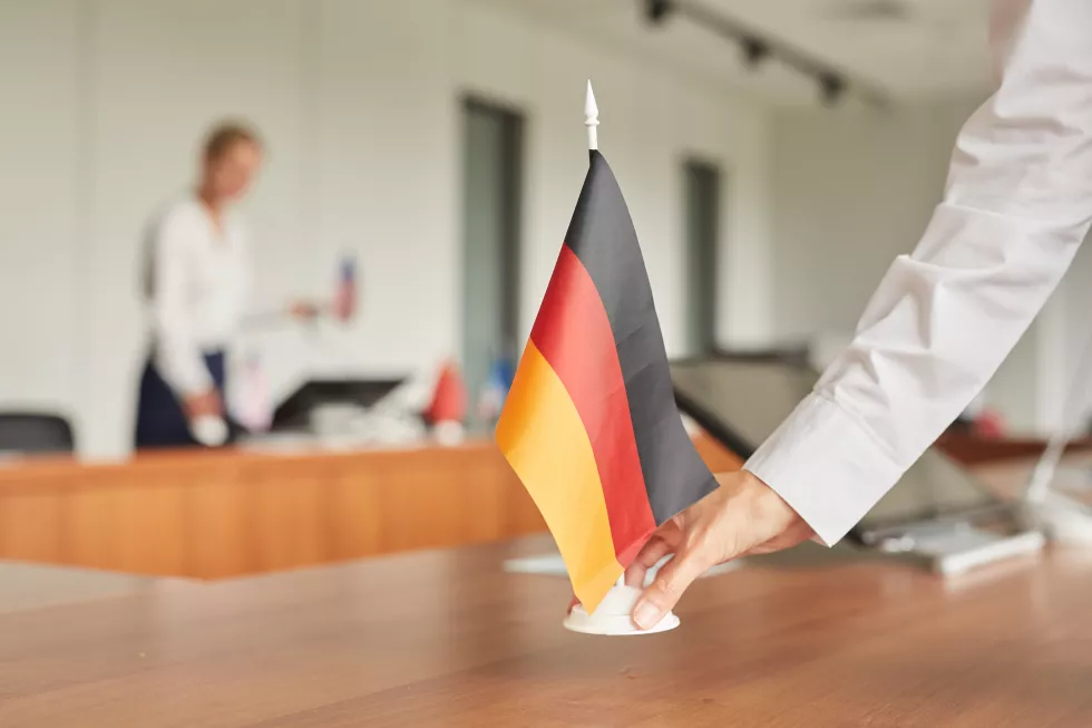close-up-female-assistant-placing-german-flag-table-while-preparing-conference-room-international-business-event