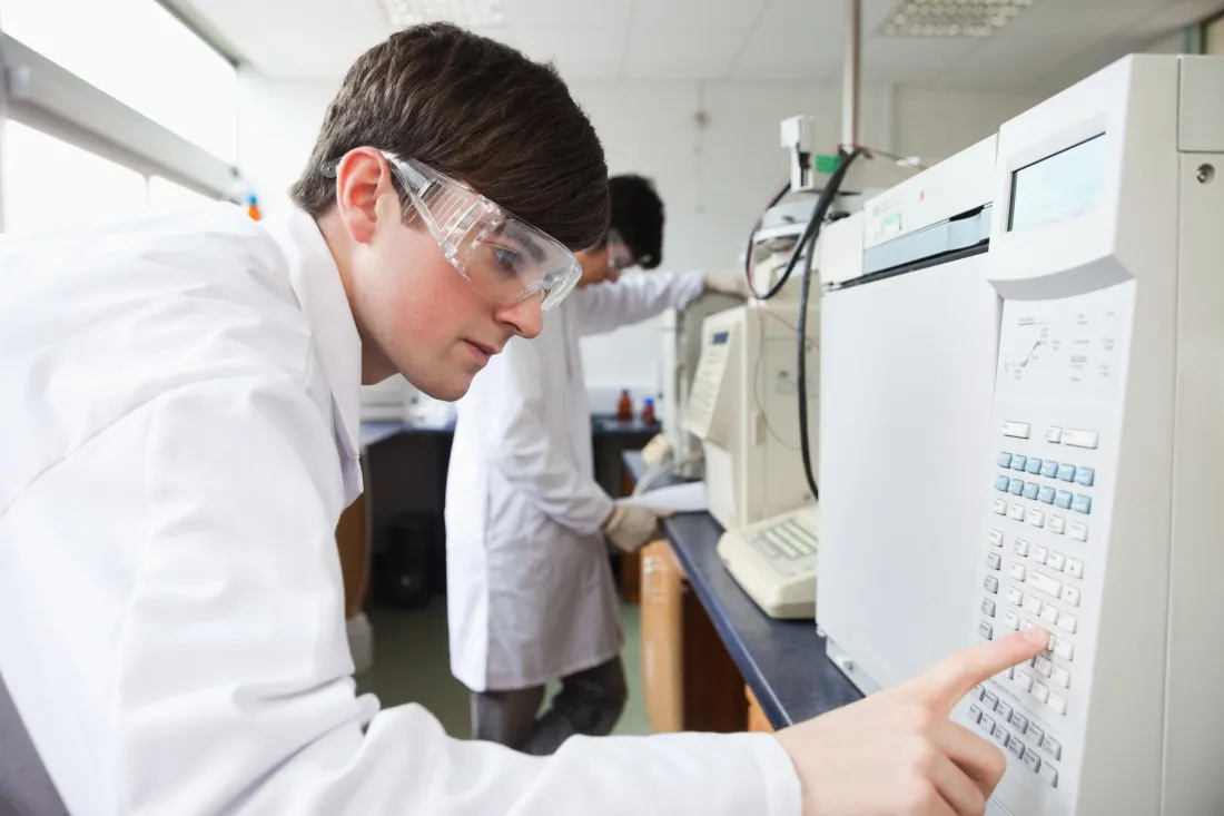Student w okularach ochronnych obsługuje aparaturę pomiarową w laboratorium