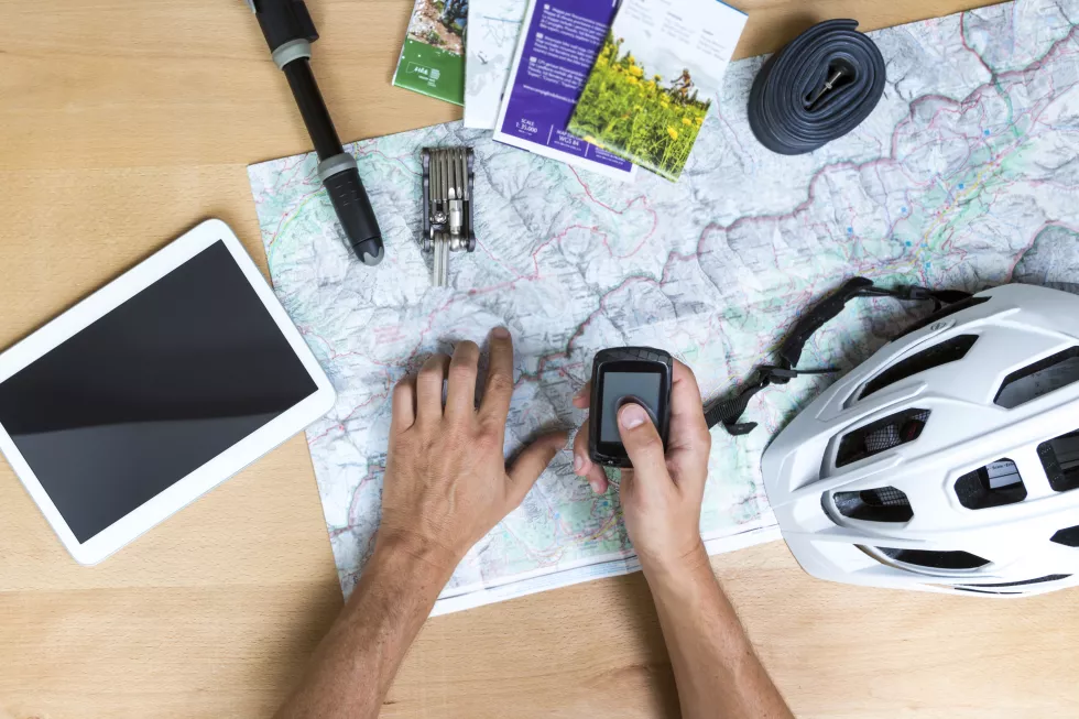 cropped-hands-man-holding-mobile-phone-map-with-digital-tablet-helmet-table