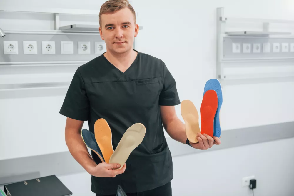 man-holding-up-pair-flip-flops-with-one-wearing-black-shirt