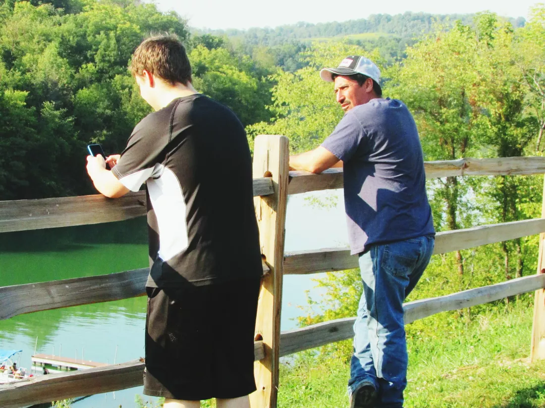 friends-standing-by-fence-front-river