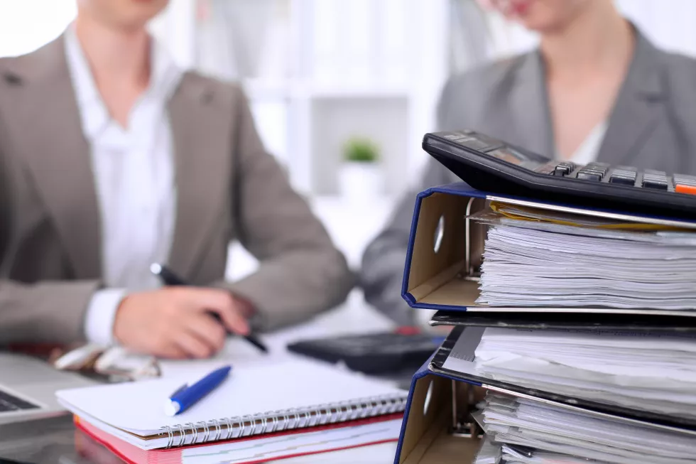 binders-with-papers-are-waiting-be-processed-with-businessman-secretary-back-blur-internal-revenue-service-inspector-checking-financial-document