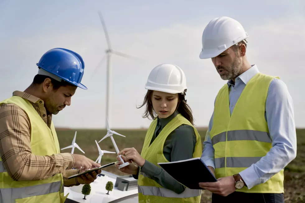 team-caucasian-latin-engineers-standing-wind-turbine-field-discussing