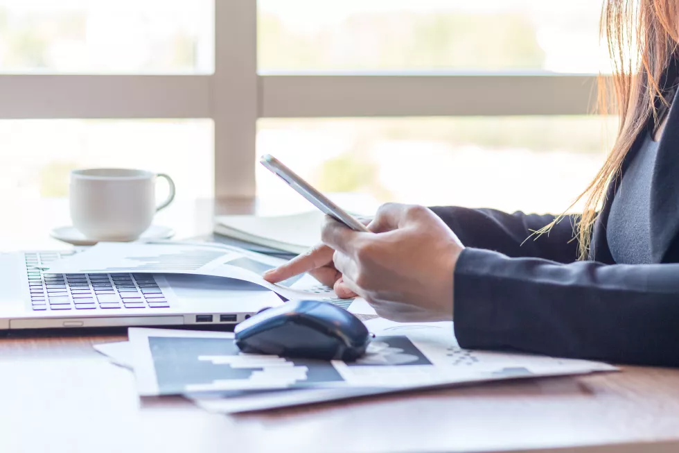 cropped-hands-businesswoman-using-phone-desk-office