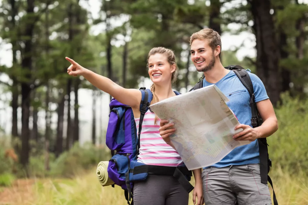 young-happy-hikers-pointing-distance-with-map