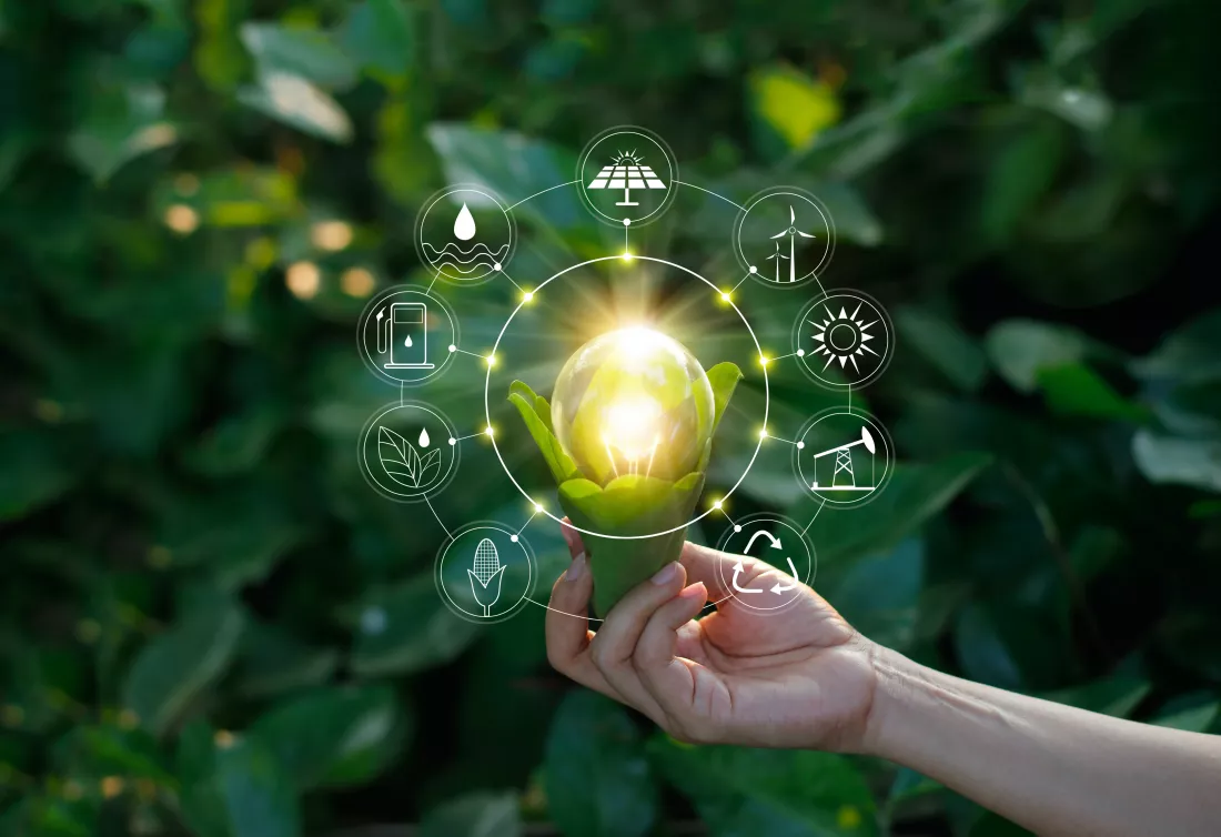 hand-holding-light-bulb-against-nature-with-icons-energy-sources-renewable-sustainable