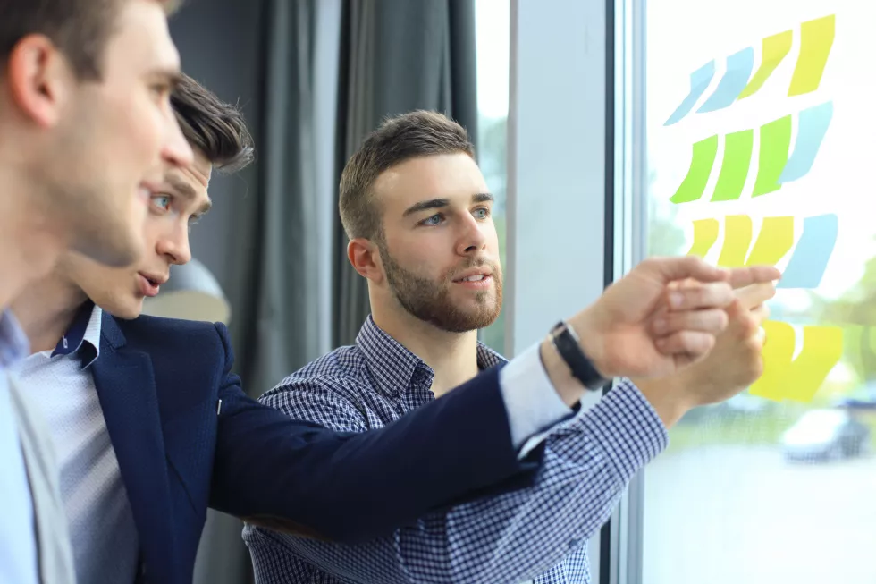 young-creative-startup-business-people-meeting-modern-office-making-plans-projects-with-post-stickers-glass