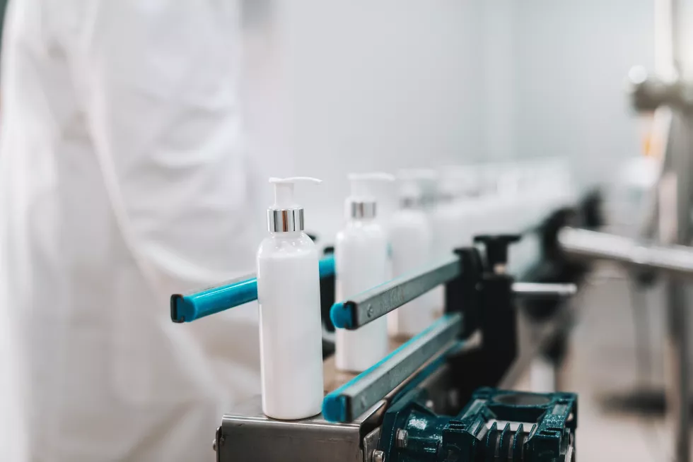close-up-bottles-with-hair-conditioner-row-exit-pouring-machine
