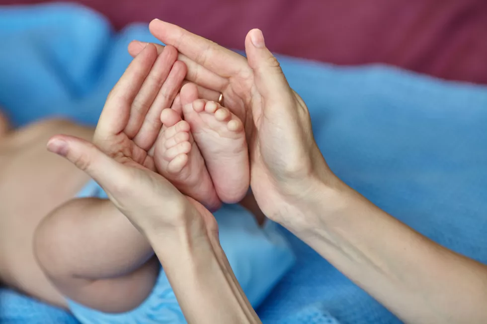 mother-s-hands-carefully-holding-baby-s-feet-selective-focus