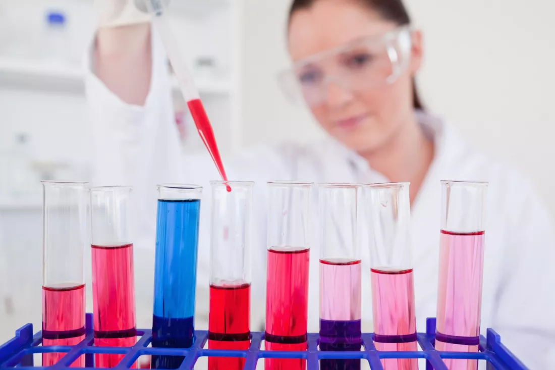 Biolożka z pipetą przy probówkach w laboratorium