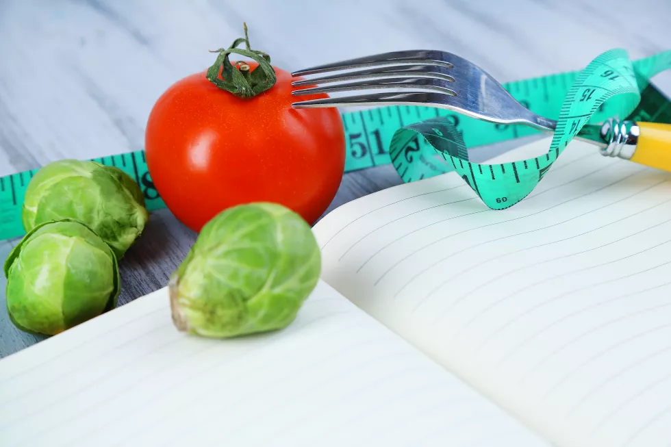 book-with-measuring-tape-vegetables-wooden-background